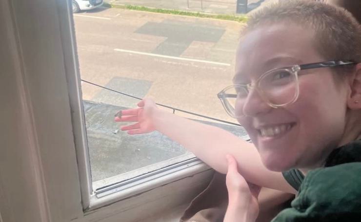 Smiling transgender person reaching out of a window