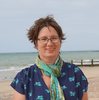 Female peer volunteer on the beach with sky in the background