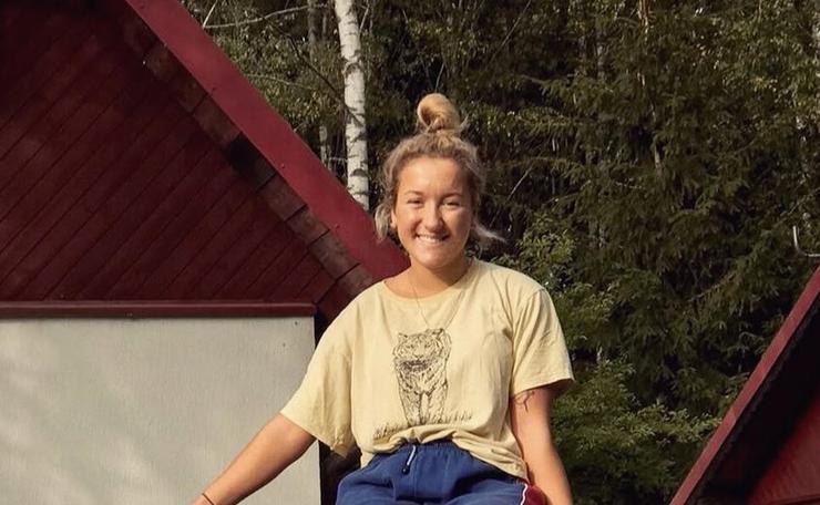 Young woman sitting on top of a bench wearing a yellow T-shirt and jeans