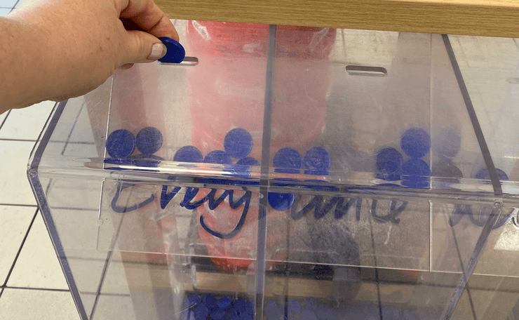Hand inserting a token in charity box in Tesco