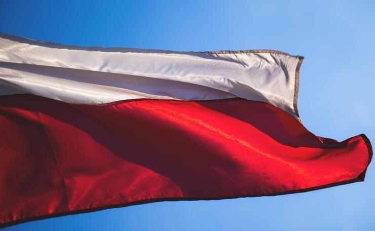 Polish flag against a blue sky blowing in the wind