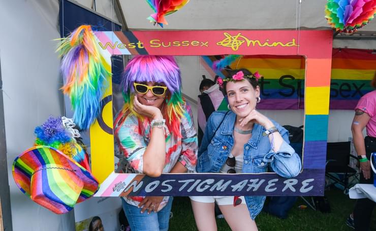 Two members of the public in a Pride colours decorated selfie frame