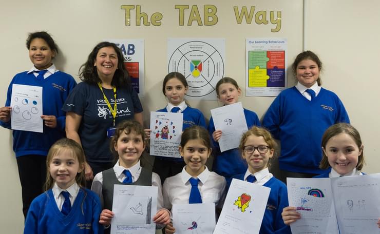 Louisa Hernandez with group of pupils holding up their designs