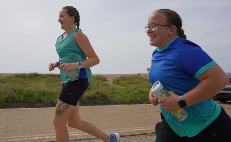 Two women running along a seafront path