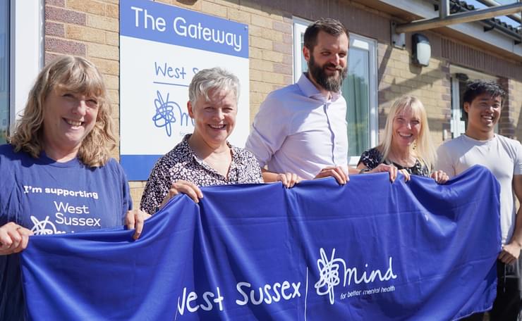 Group of West Sussex Mind staff outside Gateway building holding charity banner